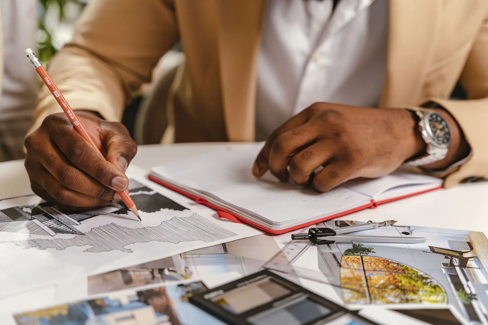 Person drawing on building plans at a desk